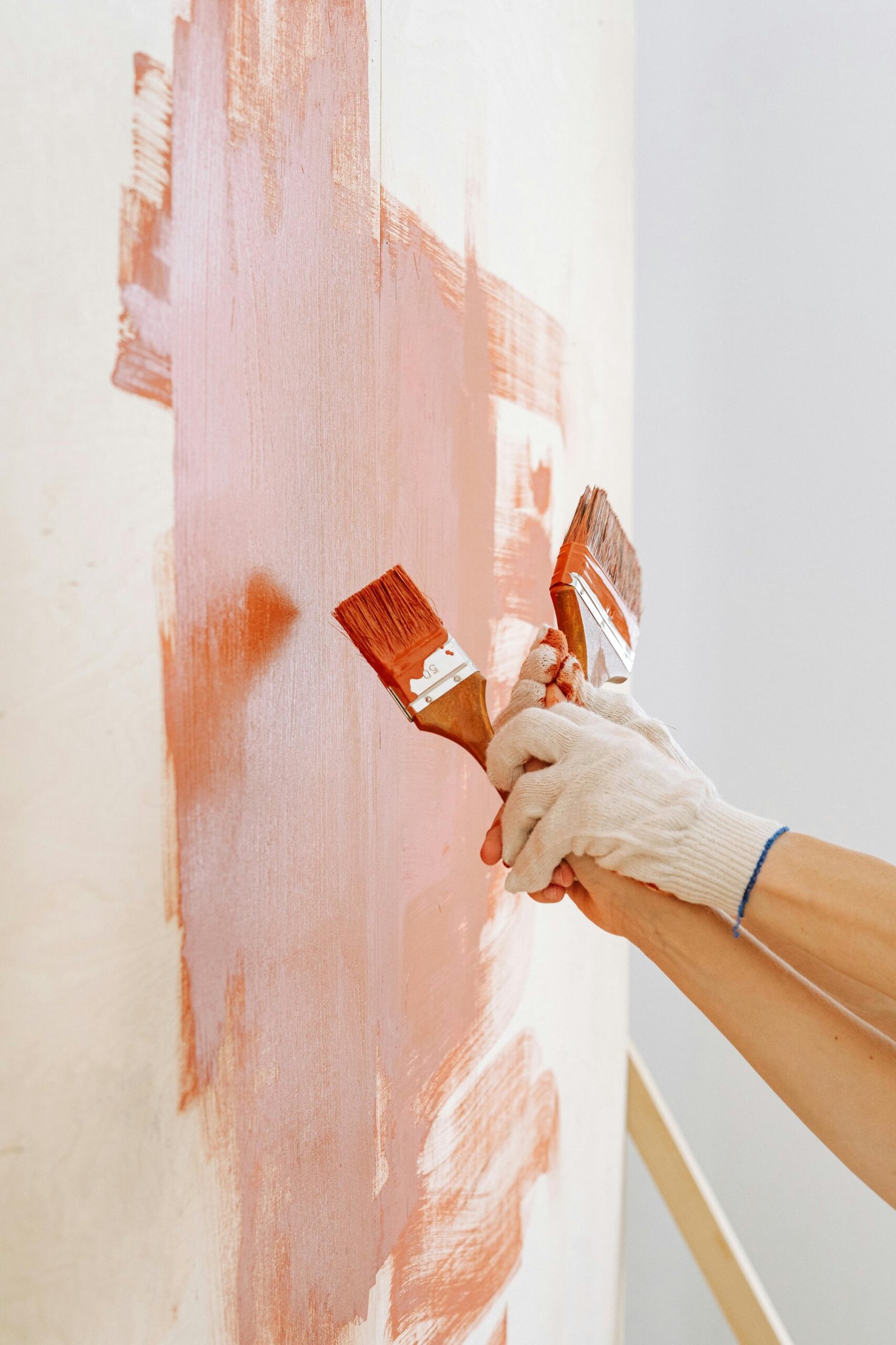 Close-up shot of hands in gloves painting a wall with wooden brushes. Perfect for DIY and renovation themes.