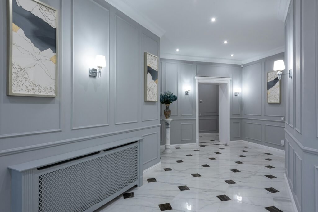 Interior of corridor of contemporary villa with shiny tiled floor and gray walls decorated with paintings and lamps